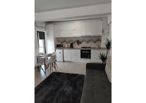 a kitchen with white cabinets and a table and chairs at Apartament Passion in Mamaia Sat/Năvodari