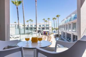 two glasses of beer sitting on a table on a balcony at Hipotels Barrosa Park in Chiclana de la Frontera