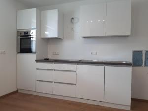 a white kitchen with white cabinets and a microwave at Ferienwohnung - Gwiggner Daniela in Niederau