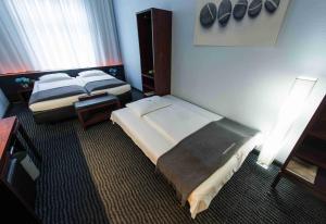 a hotel room with two beds and a lamp at Hotel Concorde in Frankfurt