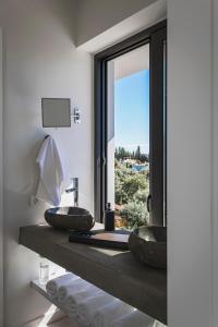 a bathroom with two sinks on a counter with a window at Villa Helena in Paleros