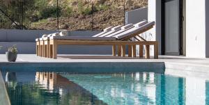 a bench next to a swimming pool next to a house at Villa Helena in Paleros