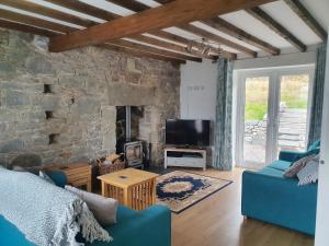 Una sala de estar con un sofá azul y una pared de piedra. en Sea Otter Cottage, en Appin