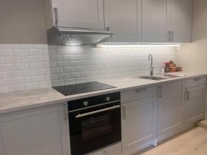 a kitchen with white cabinets and a stove and a sink at Notodden Sentrum Apartment NO 4 in Notodden