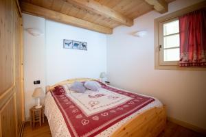 una camera da letto con un letto con una coperta rossa sopra di TRILOCALE ALPES: DIMENTICA L'AUTO E RILASSATI a Ponte di Legno