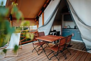 a wooden deck with a table and chairs on a tent at Lakeside Petzen Glamping in Unterlibitsch