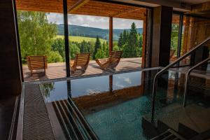 une maison avec vue sur la piscine et ses chaises dans l'établissement Amenity Hotel & Resort Orlické hory, à Deštné v Orlických horách