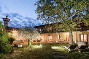 una casa con un árbol y sillas en el patio en Villa HerMes ArT, en Dutovlje