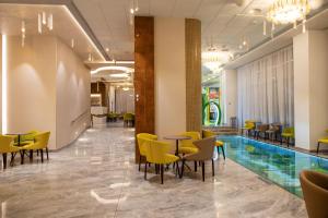a lobby with a pool and tables and chairs at Hotel Olanesti & Spa Medical in Băile Olăneşti