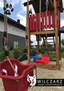 a swing with a red chair and a house at Wilczarz in Duszniki Zdrój