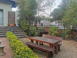 una mesa de picnic de madera y bancos en un jardín en Harties Honeymoon Suite, en Hartbeespoort