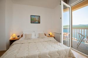 a large white bed in a bedroom with a balcony at Apartments Knežević in Neum