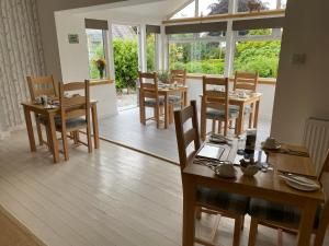 a dining room with tables and chairs and windows at Stables Guest House in Newton Stewart