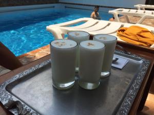 uma bandeja com três copos de leite numa mesa ao lado de uma piscina em Posada del Angel Hotel em Tarapoto