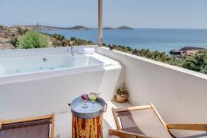 La salle de bains est pourvue d'une baignoire, de chaises et d'une vue sur l'océan. dans l'établissement Faros Resort, à Azolimnos