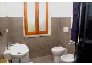 Un baño con lavabo, inodoro y ventana. en Casa vacanze a pochi passi dal mare, en La Maddalena 11 fotos más
