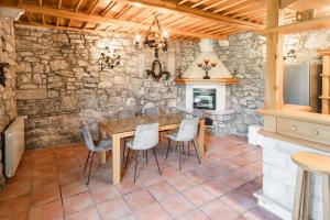 - une cuisine aux murs en pierre avec une table et des chaises en bois dans l'établissement Apartment Trieste HerMes arT, à Sežana