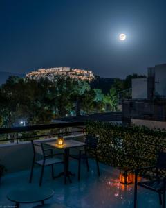 una mesa y sillas en un balcón por la noche en Acropolis Vision, en Atenas