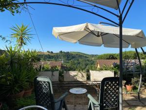 eine Terrasse mit einem Tisch, Stühlen und einem Sonnenschirm in der Unterkunft Il Cenacolo Di Sissi in Campagnano di Roma