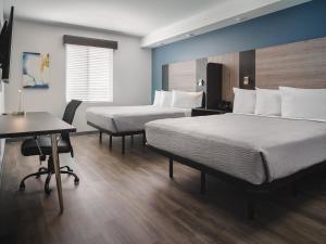 ダーラムにあるstayAPT Suites Raleigh-Durham/RTPのベッド2台とデスクが備わるホテルルームです。