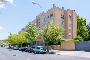 Los Robles Stylish & Modern 1 Bedroom Apartment in Madrid Conde Orgaz في مدريد: مبنى من الطوب وسيارات تقف في موقف للسيارات