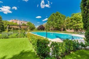 uma piscina num quintal com árvores e relva em Las Huertas - Modern Accommodation in Madrid Conde Orgaz em Madri