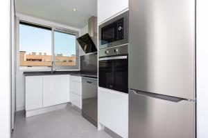 a kitchen with white cabinets and a stainless steel refrigerator at Las Encinas Design Apartment in Conde Orgaz - Madrid in Madrid