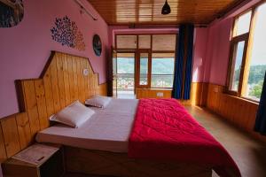 a bedroom with a large bed in a room with windows at Voyageur Nest in Manāli