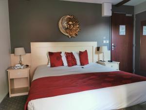 Grand-FougerayHÔTEL LES PALIS的一间卧室配有一张带红色枕头的大床
