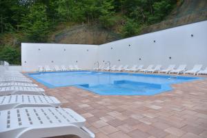 a swimming pool with white chairs and a white wall at Pollock Hotel, Ribarska Banja in Ribarska Banja