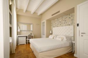 a bedroom with a large white bed and a desk at Boutique Hotel Carlo Felice in Cagliari