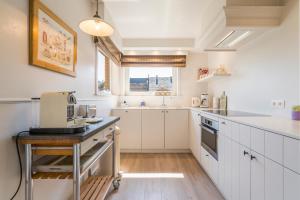 cocina con armarios blancos y encimera en Spacious, warm and updated Home w parking & garden, en Bredene