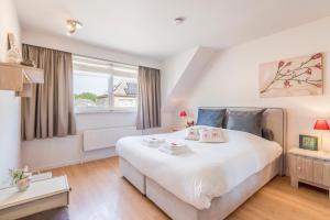 Un dormitorio con una gran cama blanca y una ventana en Spacious, warm and updated Home w parking & garden, en Bredene