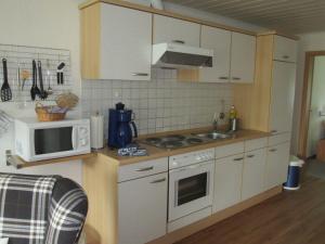 eine Küche mit einem Herd und einer Mikrowelle in der Unterkunft Wohnung Wattwurm in Süderende