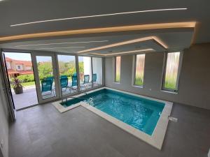 a large swimming pool in a house with windows at MAGNOLIA Room & Spa - ADULTS ONLY in Csopak