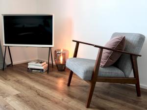 a living room with a chair and a flat screen tv at hey BEACHVILLA in Hohwacht