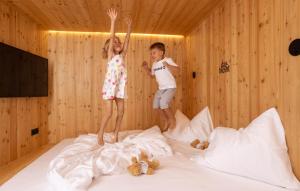 chłopiec i dziewczynka skaczący na łóżku w obiekcie das bleibt Alpine Suites w Schladming