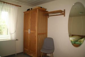 a bedroom with a mirror and a cabinet and a chair at Wohnung-Krabbe in Süderende