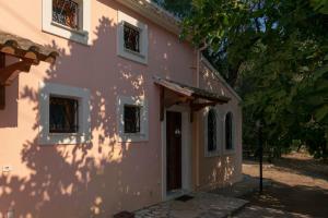 a pink building with a tree in front of it at Villa Olive apartments in Ipsos
