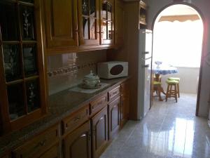 a kitchen with wooden cabinets and a white microwave at Tipical Apartment Nazare in Nazaré