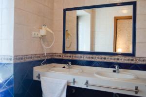 a bathroom with two sinks and a mirror at Casa del Cura in Las Navas del Marqués