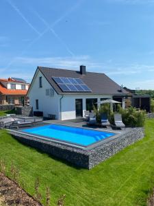 a house with a swimming pool with solar panels on the roof at hey BEACHVILLA in Hohwacht