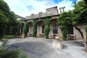 アレッサーノにあるPalazzo Ducale Sangiovanniの中庭にテーブルと椅子が置かれたツタに覆われた建物