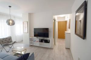 a white living room with a tv and a couch at Maximus in Čakovec