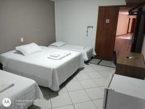 ein Hotelzimmer mit 2 Betten und einem Schreibtisch in der Unterkunft Hotel Ravenna in Divinópolis