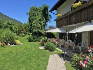 a garden with tables and chairs and an umbrella at Garni Rebhof in Nalles