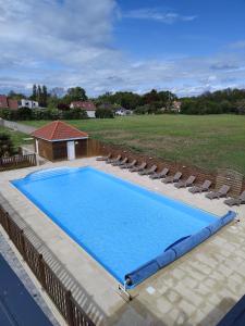 a large swimming pool with lounge chairs at Le Village du Phare in Gouville-sur-Mer