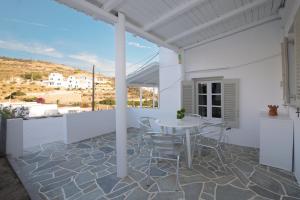 un patio blanco con mesa blanca y sillas en Prasini Gonia en Platís Yialós Sifnos