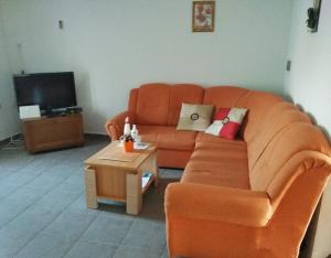 a living room with an orange couch and a table at Apartman Darko in Cesarica
