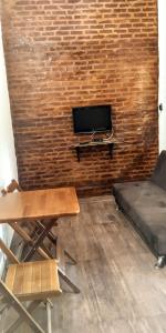 a room with a couch and a tv on a brick wall at Chalé 1 - Recanto Shambala in São Thomé das Letras